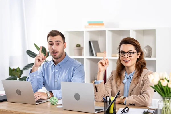 Femme surprise assis avec collègue et geste dans le bureau — Photo de stock