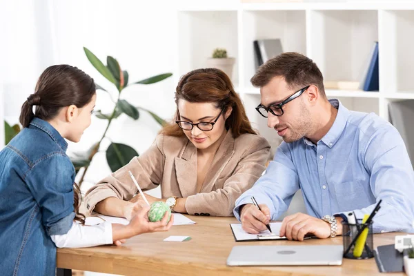 Child holding ball near mother and father in glasses — Stock Photo