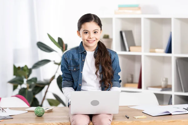 Criança alegre usando laptop enquanto sentado na mesa no escritório — Fotografia de Stock