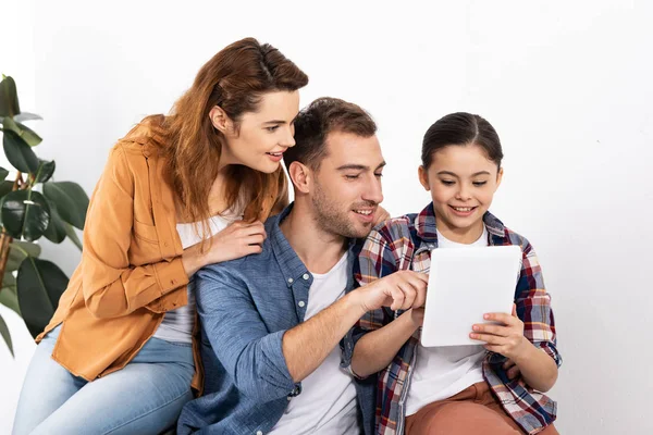 Padres felices mirando tableta digital con linda hija en casa - foto de stock