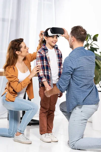Pais felizes olhando para criança alegre em fone de ouvido realidade virtual — Fotografia de Stock