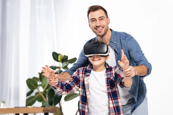 Padre feliz cogido de la mano del niño lindo en auriculares de realidad virtual - foto de stock
