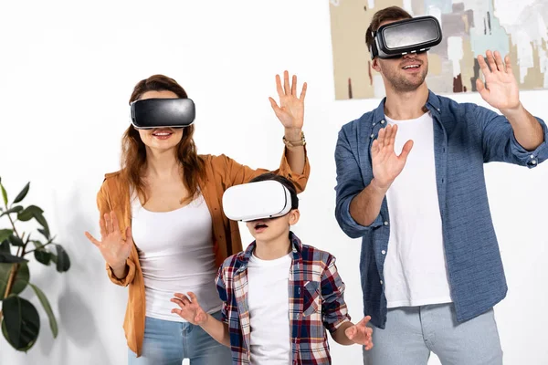 Счастливые родители и милый ребенок в наушниках виртуальной реальности дома — стоковое фото