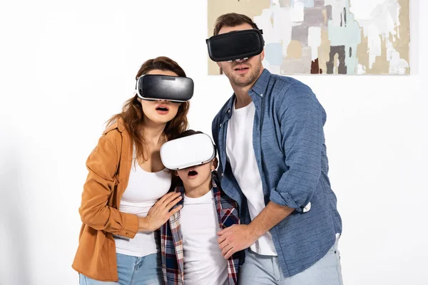 Shocked parents and surprised kid wearing virtual reality headsets at home — Stock Photo
