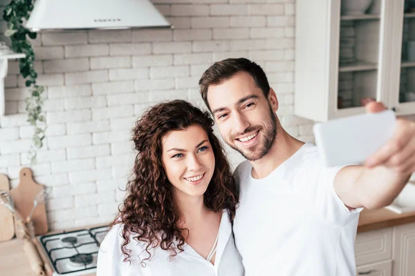 Sonriente feliz pareja tomando selfie juntos en casa - foto de stock