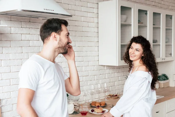 Sonriente pareja mirándose en la cocina - foto de stock
