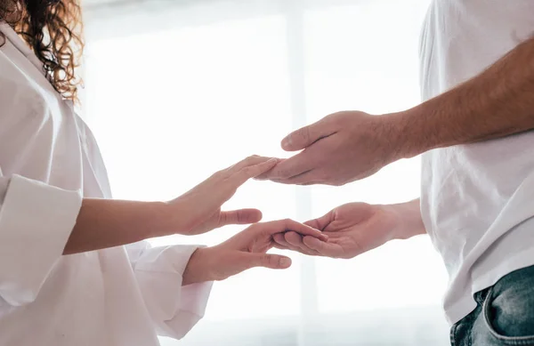 Vue partielle du couple aimant se tenant la main à la maison — Photo de stock