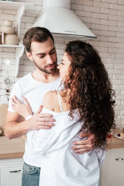 Amorosa pareja abrazándose en acogedora cocina en la mañana - foto de stock