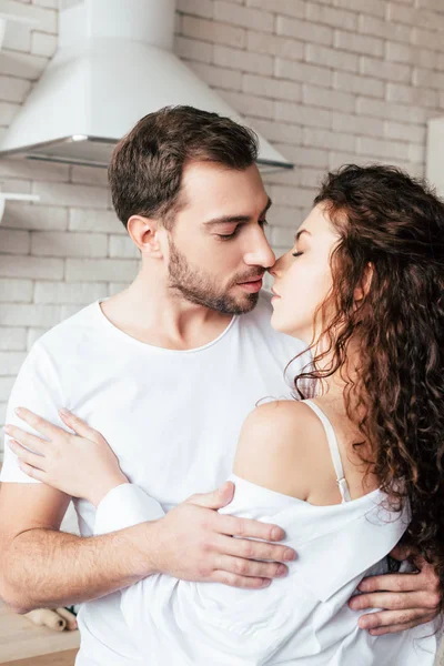 Sensual pareja abrazando con los ojos cerrados en la cocina - foto de stock