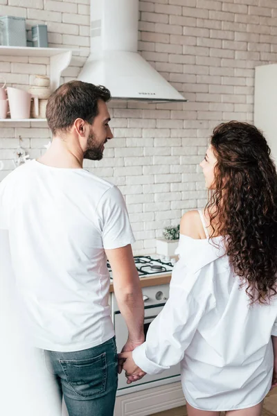 Rückansicht des Paares, das sich in der Küche an den Händen hält und einander ansieht — Stockfoto