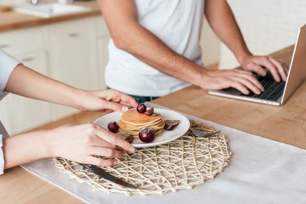 Partial view of couple with tasty pancakes and laptop — Stock Photo