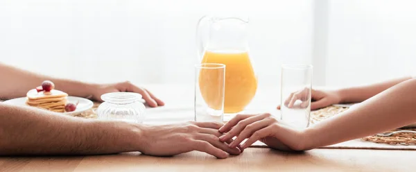 Vue panoramique de la vue partielle du couple touchant les mains pendant le petit déjeuner — Photo de stock