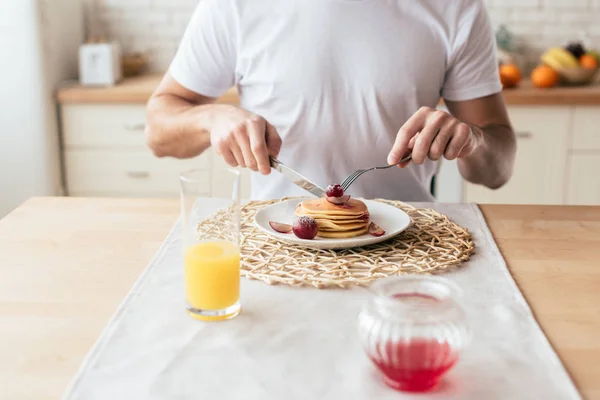 Partial view of man eating pancakes in kitchen — Stock Photo