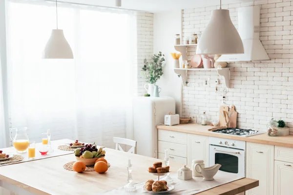 Cozinha moderna com frutas, panquecas, bolos, croissants e suco de oranje na mesa — Fotografia de Stock