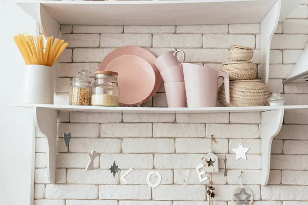 Shelf with plates, cups, jars and pasta in kitchen — Stock Photo