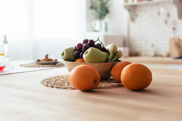 Ciotola con mele, banane, uva e arance in tavola — Foto stock