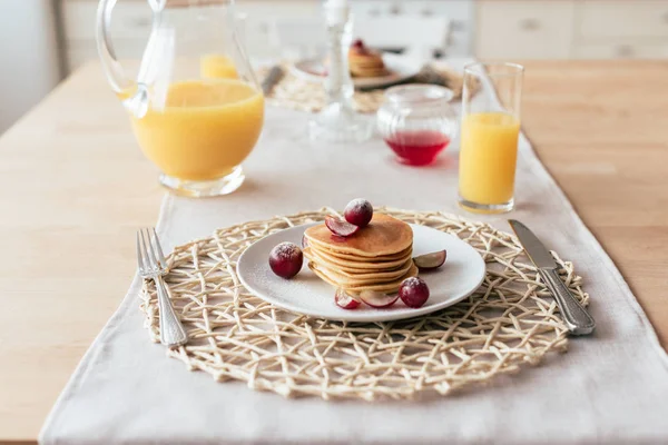 Pfannkuchen, Orangensaft, Sirup und Besteck auf dem Tisch in der Küche — Stockfoto