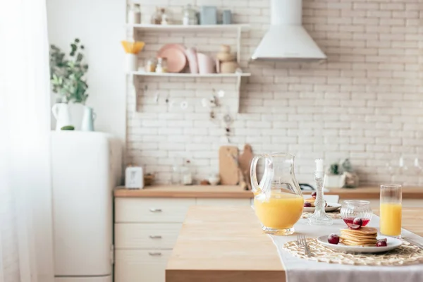 Served table with pancakes and orange juice in kitchen — Stock Photo