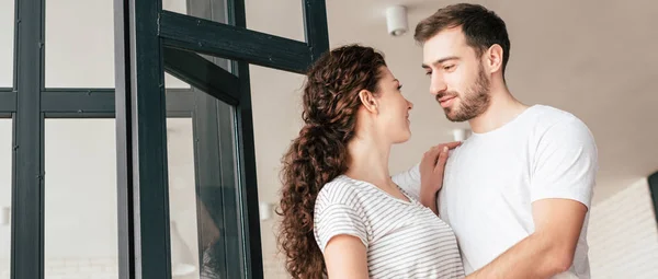 Panoramic shot of happy couple embracing and looking at each other — Stock Photo