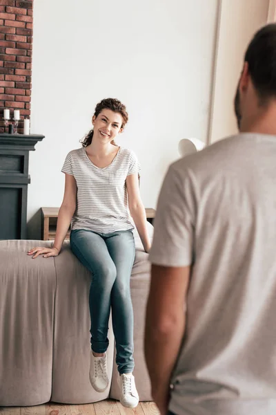 Sorrindo menina encaracolado em jeans olhando para o namorado em casa — Fotografia de Stock