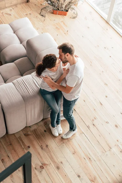 Vista aérea de pareja besándose y abrazándose en sala de estar - foto de stock