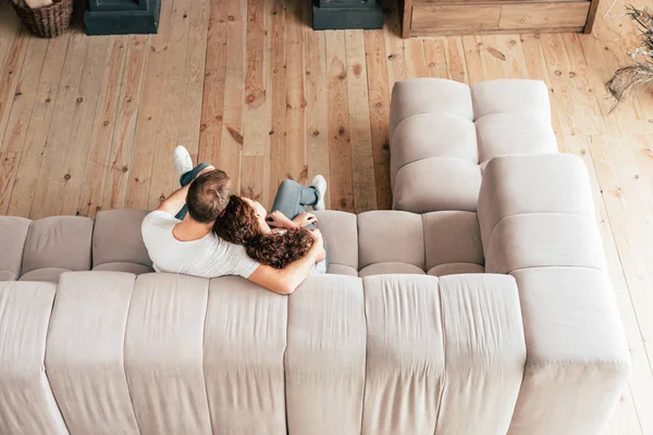 Blick von oben auf Paar, das sich auf Sofa im Wohnzimmer umarmt — Stockfoto