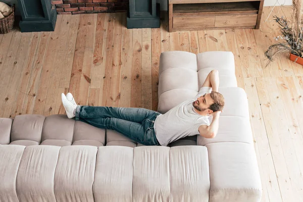 Vista aerea di rilassato uomo sorridente sdraiato sul divano — Foto stock