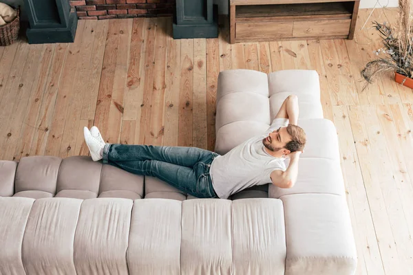 Vue aérienne de l'homme souriant détendu couché sur le canapé — Photo de stock