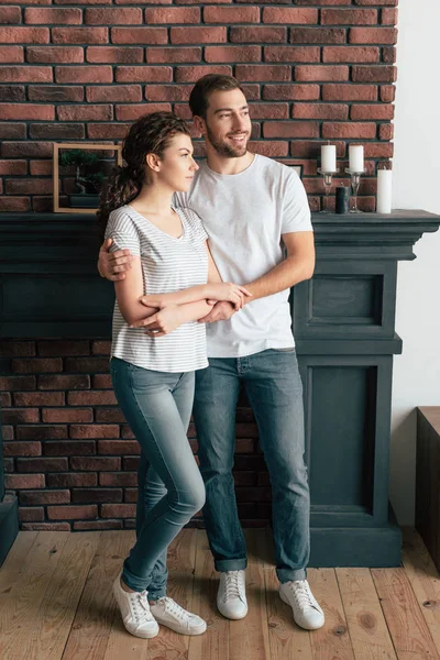 Vista completa de hombre sonriente abrazando novia y mirando hacia otro lado - foto de stock