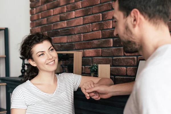 Pareja feliz tomados de la mano y mirándose en la sala de estar - foto de stock