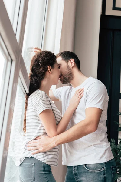 Glückliches Paar in Jeans umarmt und küsst sich zu Hause — Stockfoto