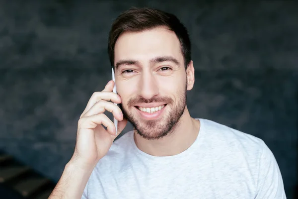 Vue de face de l'homme barbu souriant parlant sur smartphone et regardant la caméra — Photo de stock