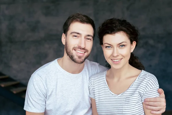 Sonriente barbudo hombre abrazando novia y mirando a la cámara - foto de stock