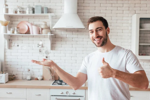 Smiling bearded man showing thumb up and looking at camera — Stock Photo
