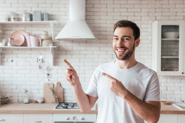 Homem barbudo sorridente apontando com os dedos e olhando para a câmera — Fotografia de Stock