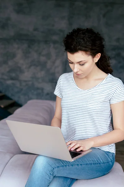 Menina concentrada usando laptop enquanto sentado na sala de estar — Fotografia de Stock