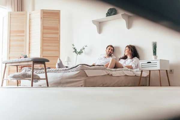 Sonriente pareja acostada en la cama y mirándose - foto de stock