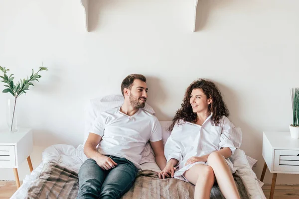 Lächelndes Paar, das auf dem Bett liegt und einander ansieht — Stockfoto