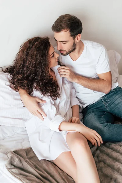 Casal amoroso abraçando e olhando um para o outro na cama — Fotografia de Stock