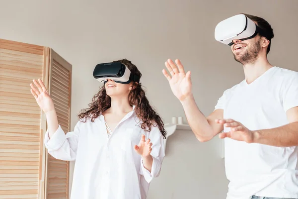 Couple in vr headsets waving hands in bedroom — Stock Photo