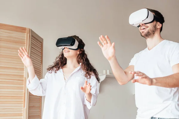 Pareja en vr auriculares agitando las manos en el dormitorio - foto de stock