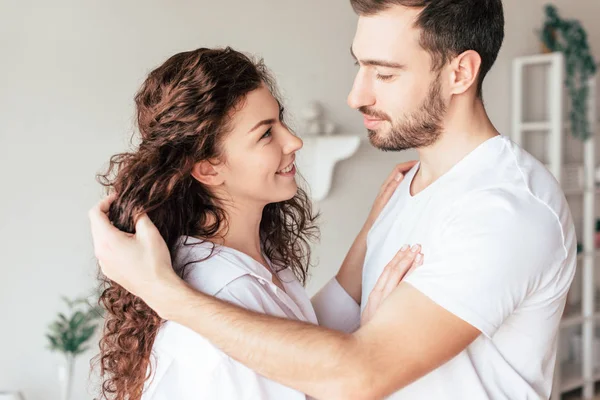 Sonriente feliz pareja suavemente tocándose en el dormitorio - foto de stock