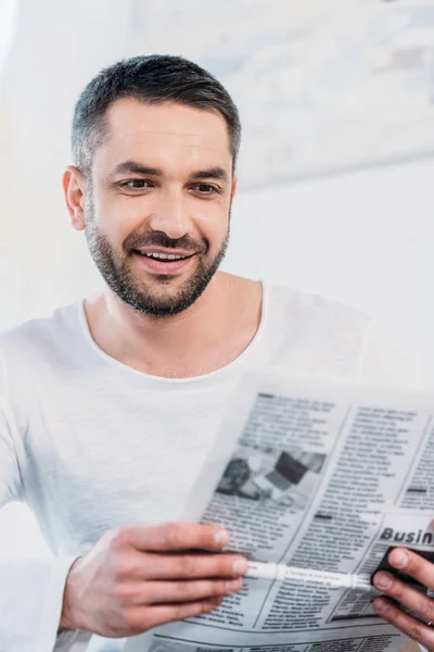 Selektiver Fokus eines gutaussehenden lächelnden Mannes, der zu Hause Zeitung liest — Stockfoto