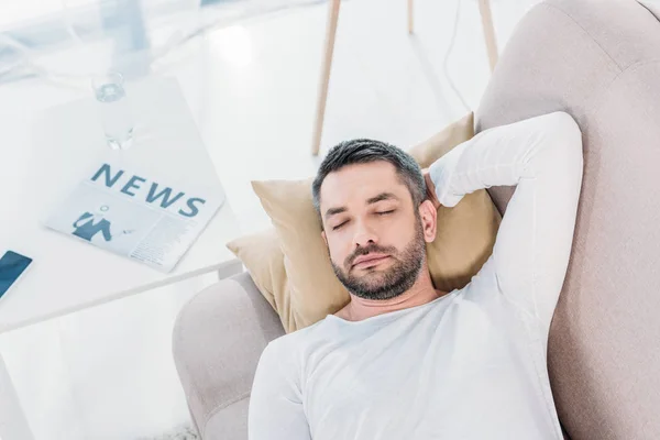 Вид зверху красивий бородатий чоловік з закритими очима відпочиває на дивані вдома — стокове фото