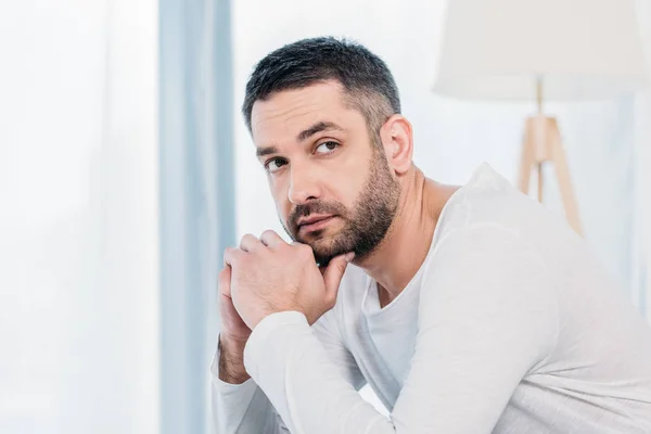 Schöner bärtiger Mann stützt Kinn mit Händen zu Hause — Stockfoto