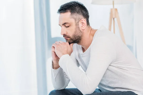 Bel homme barbu avec les yeux fermés appui menton avec les mains à la maison avec espace de copie — Photo de stock