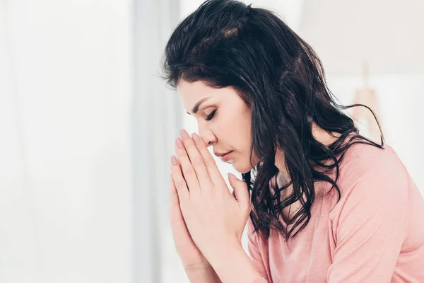 Beautiful woman with eyes closed doing please gesture and praying at home with copy space — Stock Photo