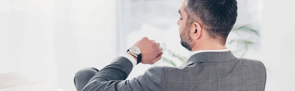 Panoramaaufnahme eines Geschäftsmannes, der auf die Uhr schaut und die Uhrzeit überprüft — Stockfoto