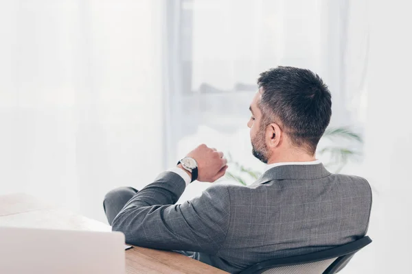 Vista trasera del hombre de negocios mirando el reloj y comprobando el tiempo en la oficina - foto de stock