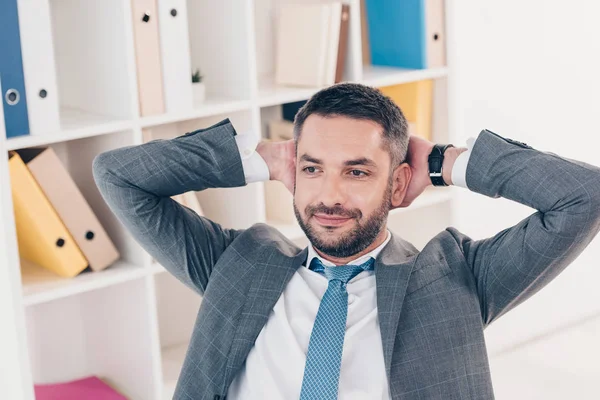 Bell'uomo d'affari in giacca e cravatta con le mani dietro la schiena in ufficio — Foto stock